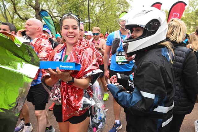 Runner Rachel from Surrey recieves her Domino's pizza after tapping a sign during the TCS London Marathon