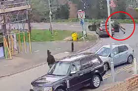 Police officer clings to car roof as suspect speeds off.
