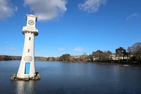 A white clock tower surrounded by water in a serene location