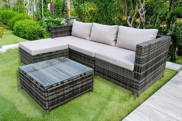 The rattan garden furniture set includes cushioned seating, ottoman stools and a tempered glass table.