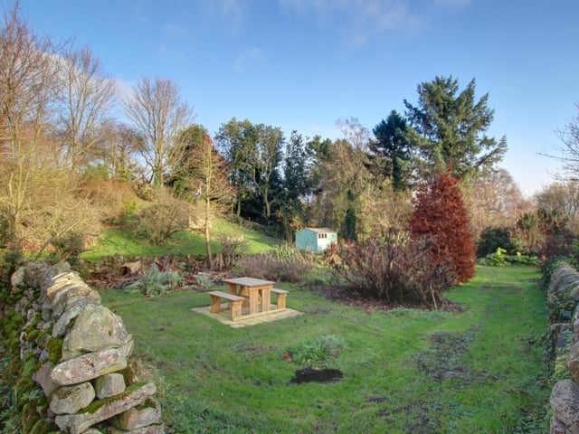 Varied tree types and stone walls pepper the grounds.
