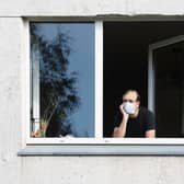 A man wearing a face mask looks out of his flat window. Photo: Shutterstock