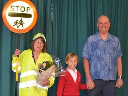 Pictured with lollipop lady Carole Hicks are Paul Allen (far right), who attended the school in 1981 when Carole first started in her role, and his son Elwood (middle) who attends the school