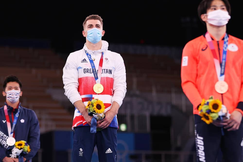 Max Whitlock stands on the top podium after he defended his Olympic pommel horse title