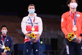 Max Whitlock stands on the top podium after he defended his Olympic pommel horse title