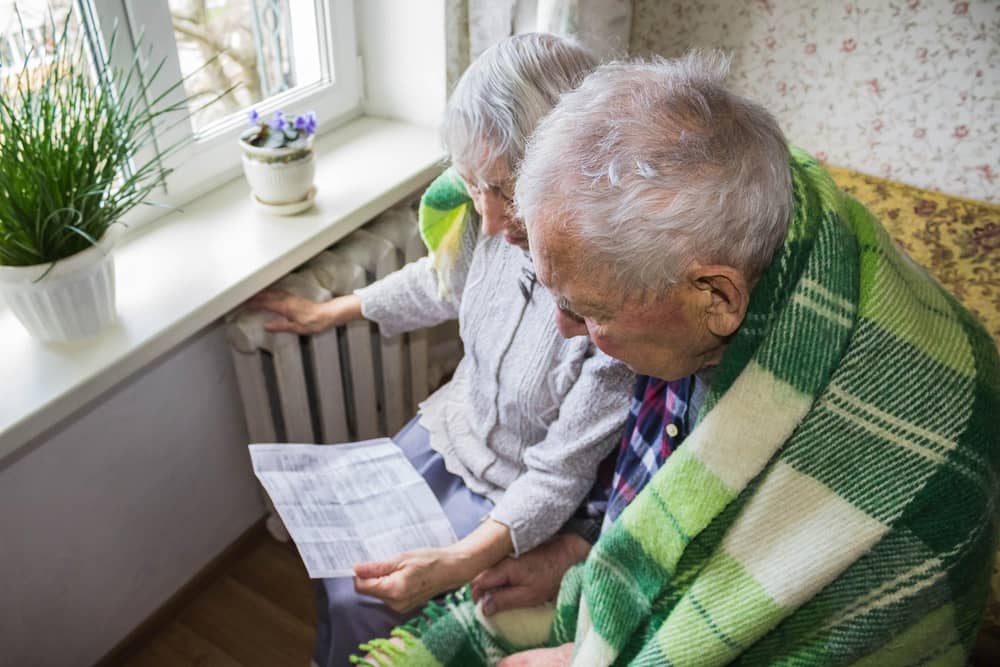 File photo of an elderly woman holding gas bill in front of radiator