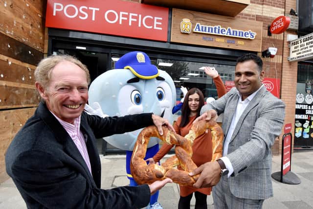 Robert Burton (left), from Auntie Anne's pulls apart a giant pretzel with new owner Saf Abdeen.