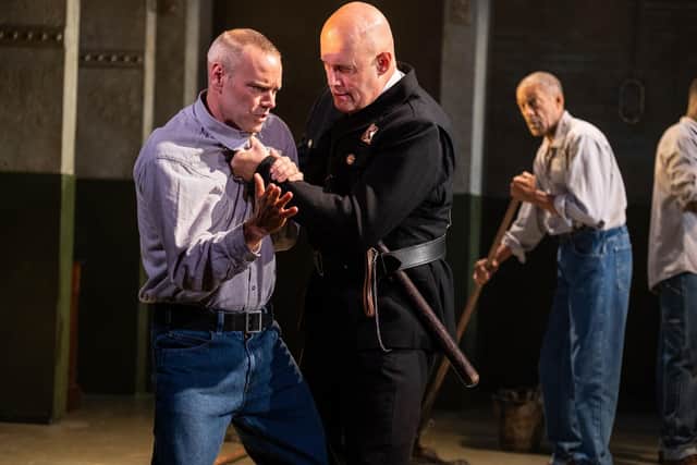 Prison guard Hadley (Joe Reisig) grabs Andy (Joe Absolom) while ‘Red’ (Ben Onwukwe) looks on
