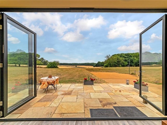 The bifold doors open onto the terrace which gets the morning sun, and a glazed door in the right-hand wall leads to a large south-facing terrace. Underneath this is an underground garage for three cars, a workshop, shower, and wine cellar.