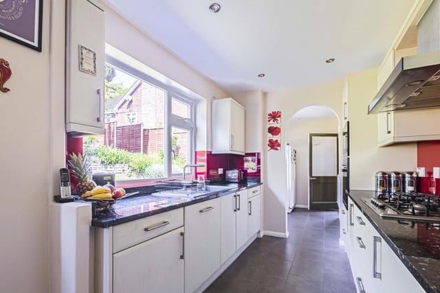 The galley-style kitchen, which is fitted with red tiles and white cupboards and leads seamlessly into the breakfast area.