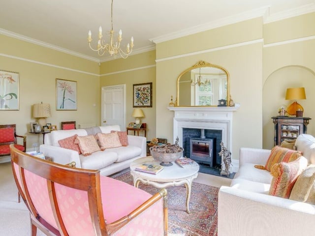 Here is the drawing room with a log burning fireplace and a large bay window.