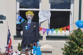 A scarecrow of Boris Johnson seen with bottles of wine and party decorations.