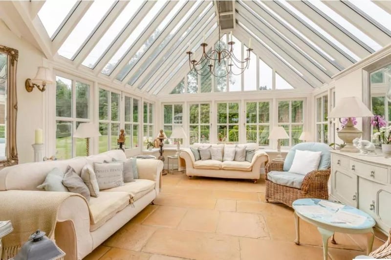 An airy treble glazed conservatory with vaulted glass ceiling and French doors opening onto the garden