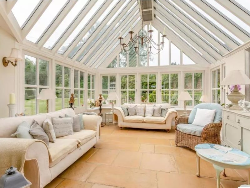 An airy treble glazed conservatory with vaulted glass ceiling and French doors opening onto the garden
