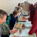 Leslie Tate helps a contestant grappling with a problem at the first Chess for Climate event at Berkhamsted's Open Door