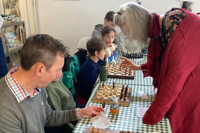 Leslie Tate helps a contestant grappling with a problem at the first Chess for Climate event at Berkhamsted's Open Door
