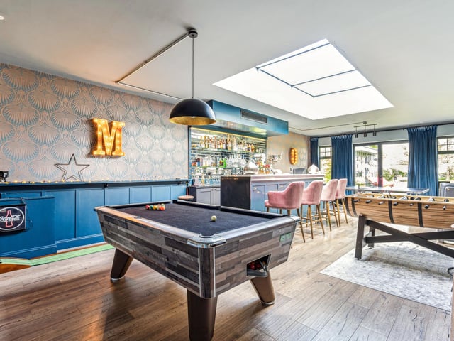 The fantastic games room is spacious and  features half panelled walls, a bespoke fully fitted bar with seating, a further roof lantern and doors opening out on to the rear garden.