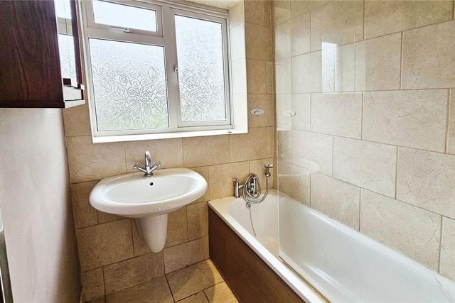 The family bathroom is fully tiled including a large sink, inset bath, a toilet and heated towel rail.