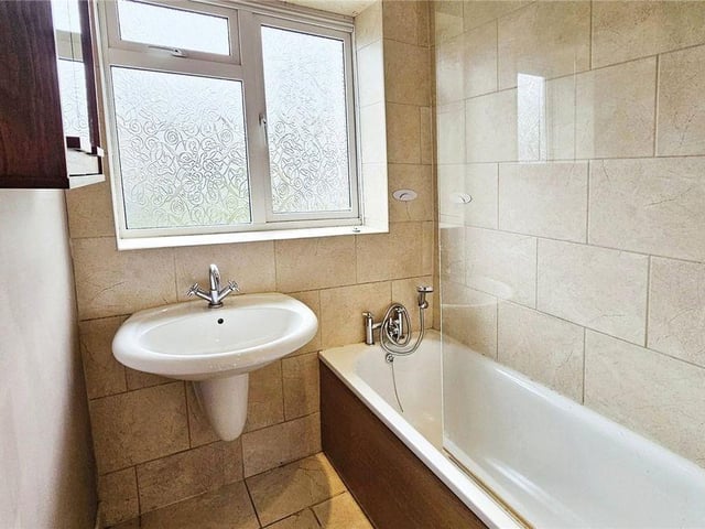 The family bathroom is fully tiled including a large sink, inset bath, a toilet and heated towel rail.