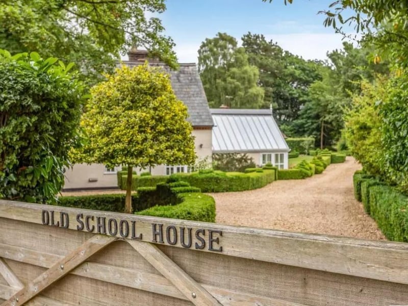 The wooden gates open onto a gravel driveway
