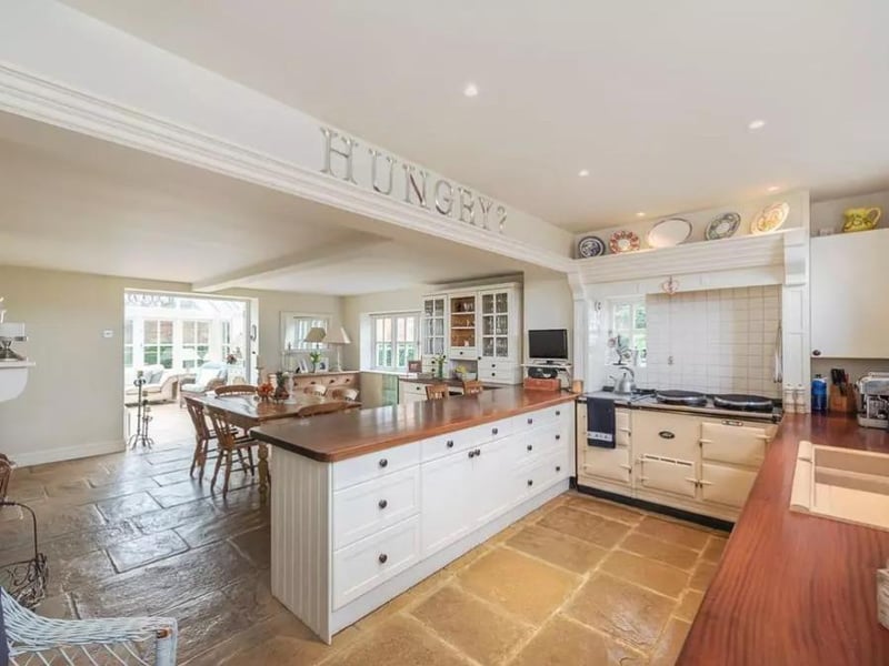 The kitchen has a breakfast bar, fitted units, an AGA, and a log burner