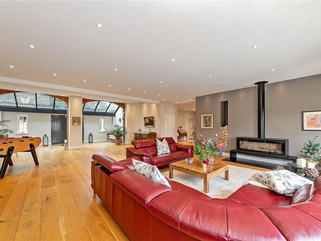 The doors of the home open onto a spacious living room. As you enter, a sloping glass roof section casts light across the original features - two curved brick arches that were the entrances to the coach house, and a well in the floor covered with a glass.