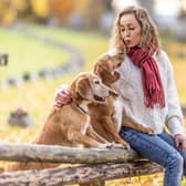 A young woman sits in the park with her dogs and shows them love (photo: Adobe)