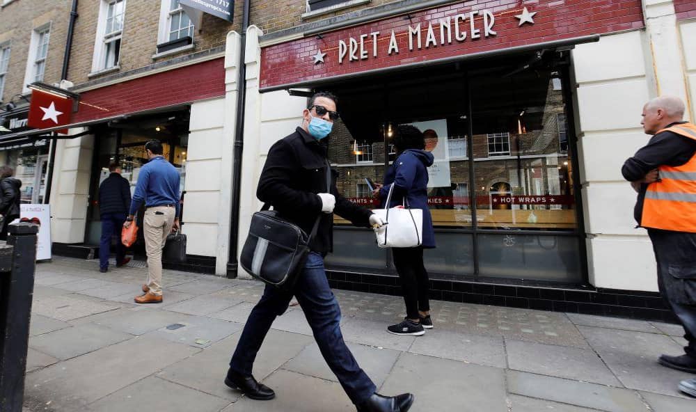 A man wearing PPE (personal protective equipment) passes customers queuing to enter a recently re-opened Pret-A-Manger shop which had originally closed-down due to the COVID-19 pandemic in London (Photo: TOLGA AKMEN/AFP via Getty Images)