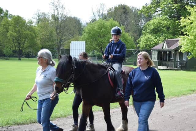 Members of Gaddesden Place RDA take one of its members on a guided horse ride
