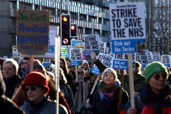 People hold placards as they take part in a protest march. (Photo by CARLOS JASSO/AFP via Getty Images)