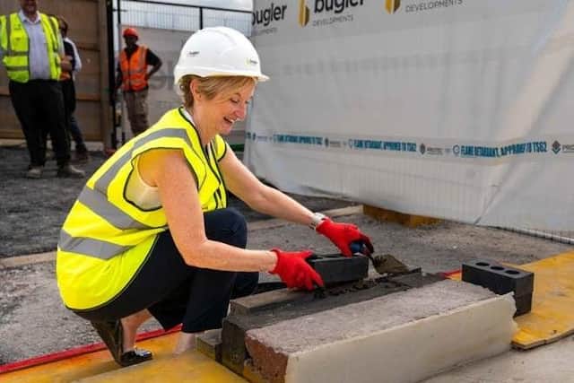 DENS CEO Wendy Lewington laying a brick to mark the progress