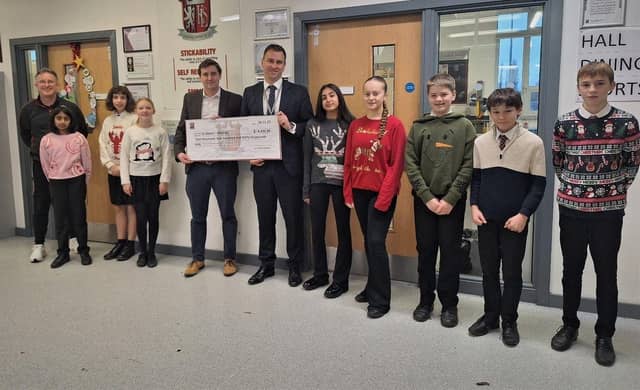 David Keen (chair of St Albans Mencap) receiving the donation from Mr Fisher (Headteacher), Mr Annett (teacher and event organiser) and some of the pupils who took part in the event.