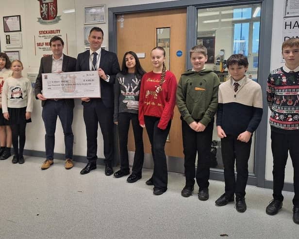 David Keen (chair of St Albans Mencap) receiving the donation from Mr Fisher (Headteacher), Mr Annett (teacher and event organiser) and some of the pupils who took part in the event.