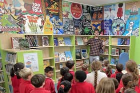 Jamie unveils the mural as pupils and Pixie the dog look on