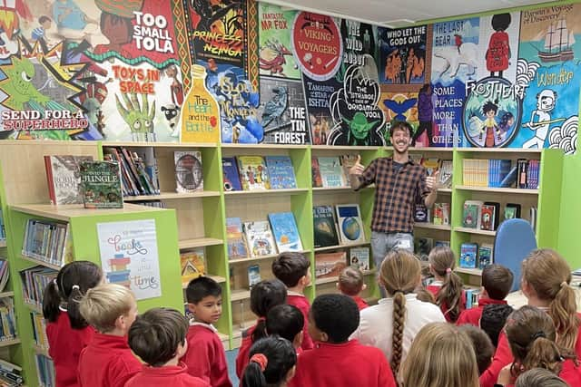 Jamie unveils the mural as pupils and Pixie the dog look on