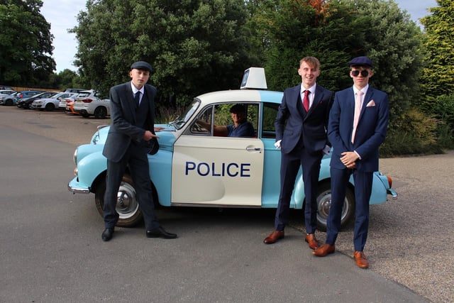 Three teenagers came to the prom in a vintage police car, wearing flat caps.