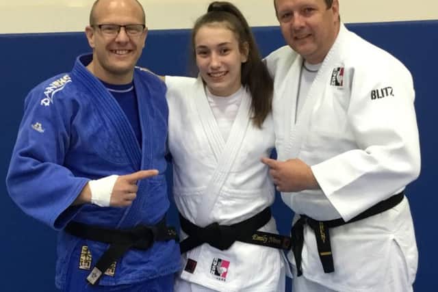 Emily being awarded her black-belt by coaches Laurie Rush and Pete Brent.