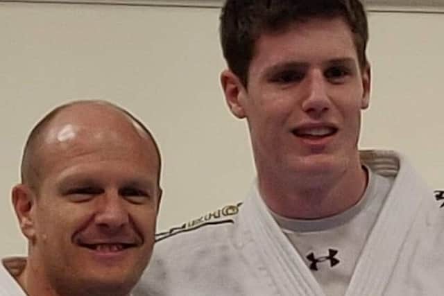 Sam Collins, right, is presented with his black-belt by coach Laurie Rush.