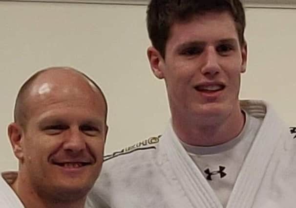 Sam Collins, right, is presented with his black-belt by coach Laurie Rush.