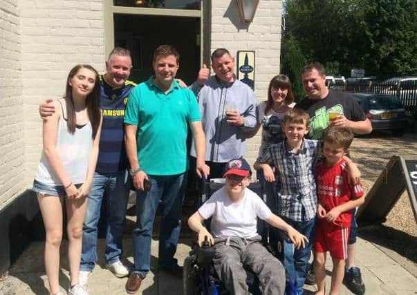 Jamie with his new wheelchair along with his family, pub landlord Clive Coules, Richard Duncan, Dave Whicker and customers.