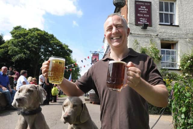 The Rising Sun's licencee Mark Granger with glasses of beer and cider and his Weimaraner dogs Willow, left, and Delkeigh.