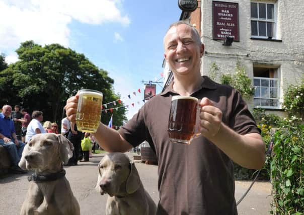 The Rising Sun's licencee Mark Granger with glasses of beer and cider and his Weimaraner dogs Willow, left, and Delkeigh.