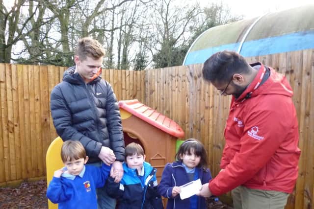 Mansoor hands the cheque to Ella Maiya Porte, Aaron Judge and Nathan Stanley with staff member Ryan Locke