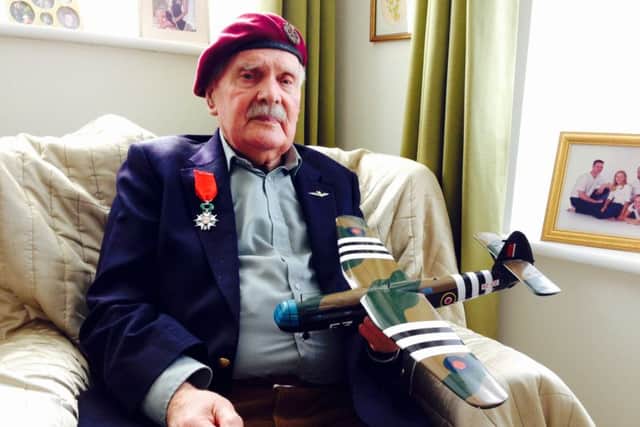 Glider pilot Michael Brown, a former Prisoner of War, wears his Legion d'Honneur medal and holds a model of a Horsa aircraft - the same as the one he learned to fly in the Second World War