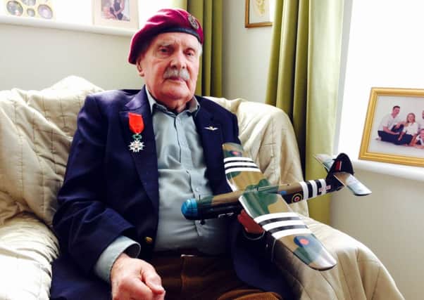 Glider pilot Michael Brown, a former Prisoner of War, wears his Legion d'Honneur medal and holds a model of a Horsa aircraft - the same as the one he learned to fly in the Second World War