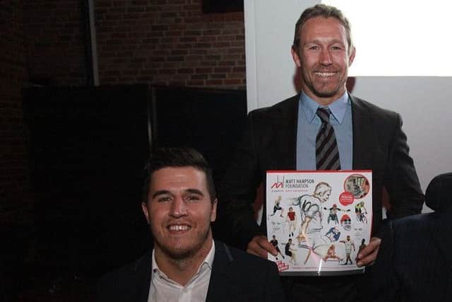 Rugby legend Jonny Wilkinson holds a charity calendar by Henry Fraser (left)