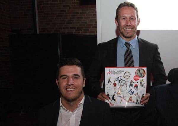Rugby legend Jonny Wilkinson holds a charity calendar by Henry Fraser (left)
