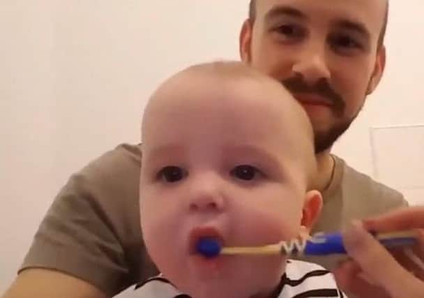 Tim Capps helps baby son Edison brush his teeth