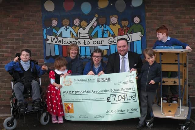 Adam Ginder presents the cheque to Woodfield's deputy head teacher Beverley Hamilton as students look on
